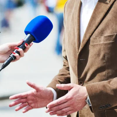 Nærbilde av blå mikrofon som intervjuer en mann