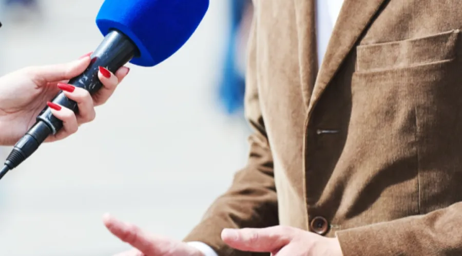 Nærbilde av blå mikrofon som intervjuer en mann